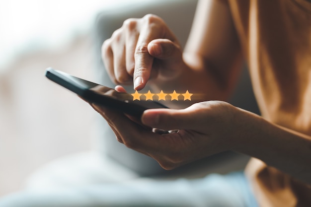 Photo close up of woman customer giving a five star rating on smartphone. review, service rating, satisfaction, customer service experience and satisfaction survey concept.