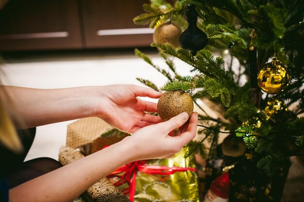 Foto close-up di una donna che decora l'albero di natale a casa