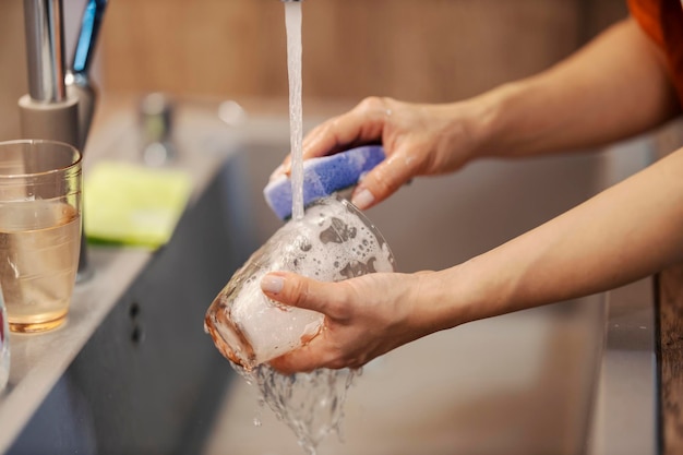 Close up of a woman doing dishes in sink