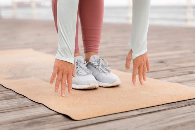 Chiuda sulla donna che fa yoga sulla stuoia