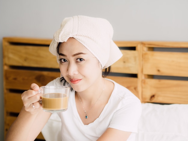 Close up of woman drink morning coffee and relax on her bed after shower.