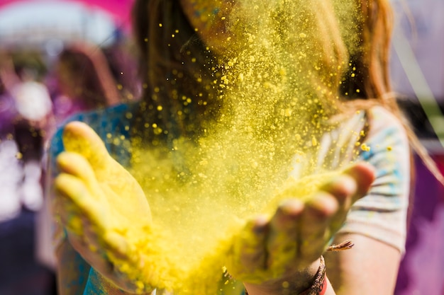 Close-up of a woman dusting the yellow holi color