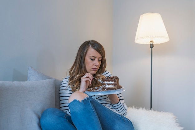 Chiuda in su della donna che mangia la torta di cioccolato.