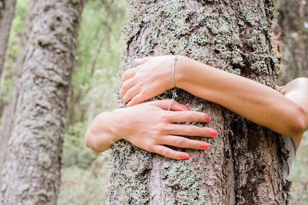 Primo piano di una donna che abbraccia un albero in un parco