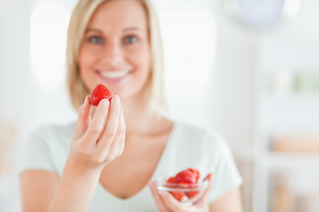 カメラに入っているイチゴを食べるのを楽しむ女性の近く