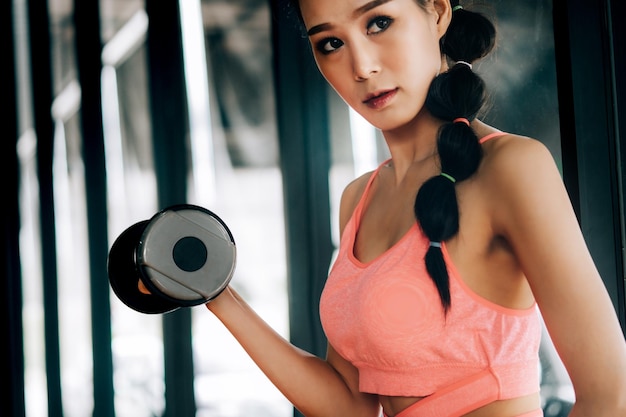 ジムでダンベルで運動する女性のクローズアップ