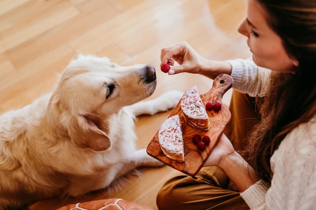 close-up of woman feeding raspberry to dog at home