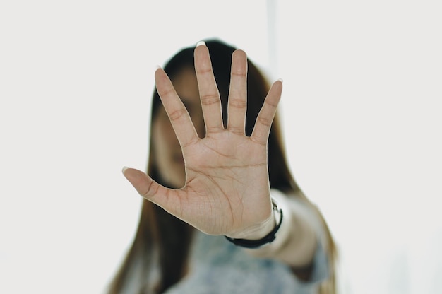 Close-up of woman gesturing stop sign against white background