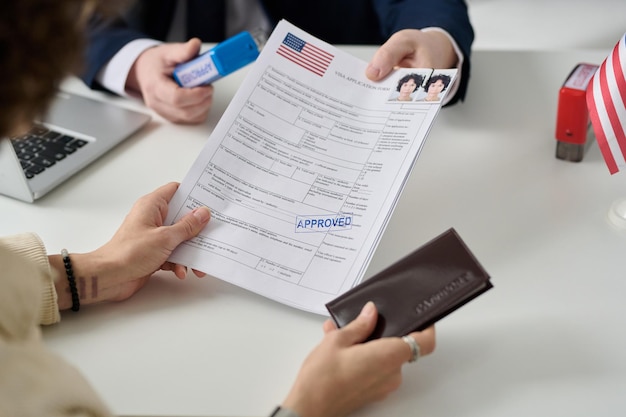 Close up of woman getting us visa in immigration office and\
holding approved forms