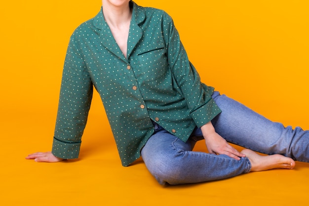 Close-up of woman in green home wear. Isolated on yellow wall with copy space.