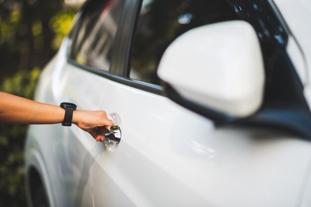 Close up woman hand on handle for opening a car door for\
driving