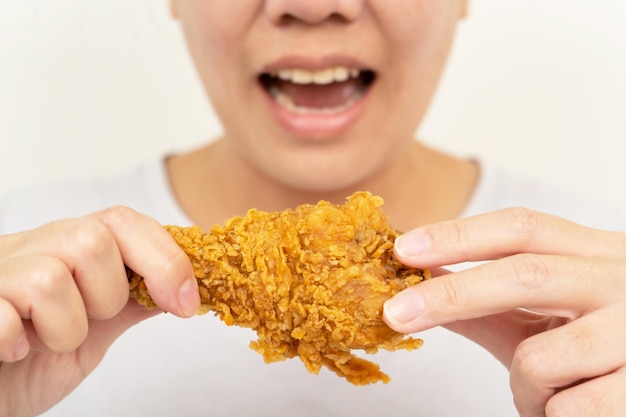 Chiuda sul pollo fritto della tenuta della mano della donna per mangiare, donna con il concetto degli alimenti a rapida preparazione