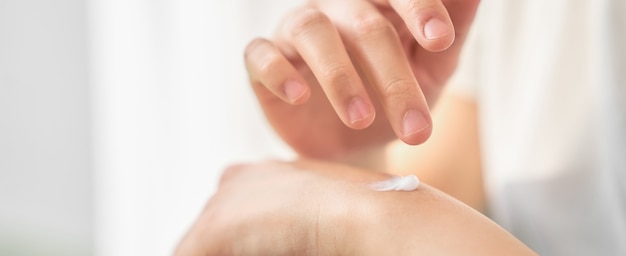 Close up of woman hand holding and applying moisturiser.