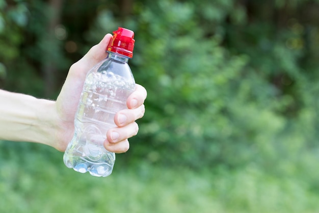 Close-up of woman hand holding bottle against blurred background