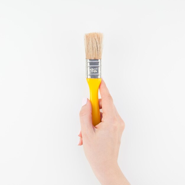 Foto close-up della mano di una donna che tiene un pennello contro uno sfondo bianco