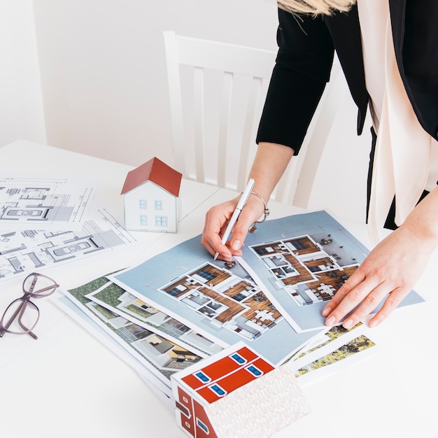 Close-up of woman hand holding pen working on blueprint in office