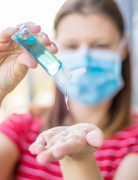 Close Up of Woman Hand Holding Sanitizer Alcohol Gel Dispenser Against 2019-nCoV