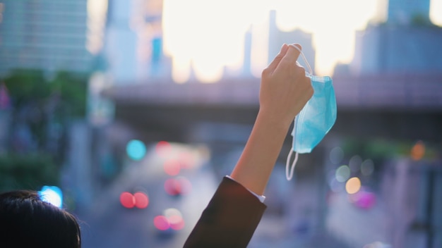 Close up woman hand is holding surgical mask, taking off face\
mask