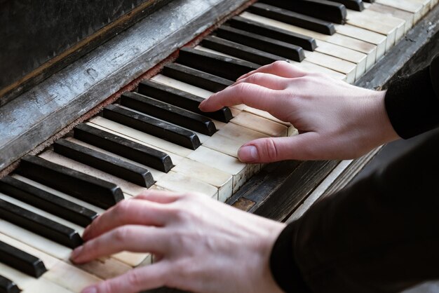 Close up woman hand plays piano touching damaged keys of old\
piano