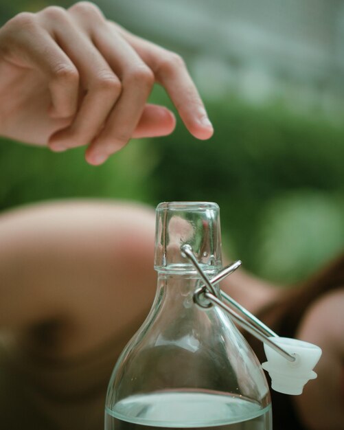 Photo close-up of woman hand touching glass bottle