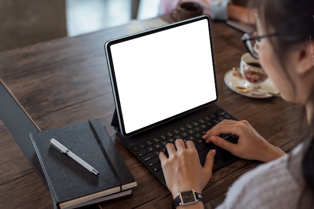 Close up. Woman hand typing on digital tablet keyboard with blank screen on desk at office.