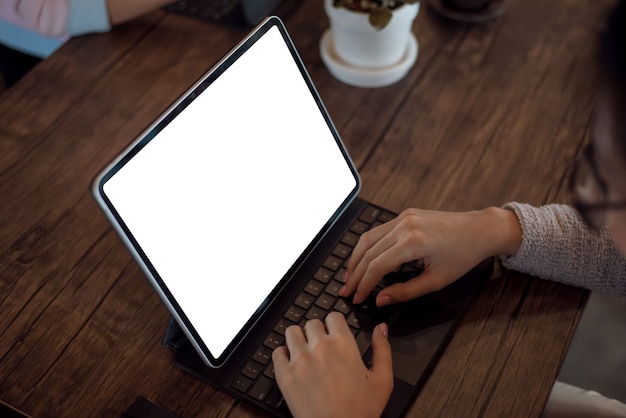 Close up. Woman hand typing on digital tablet keyboard with blank screen on desk at office.