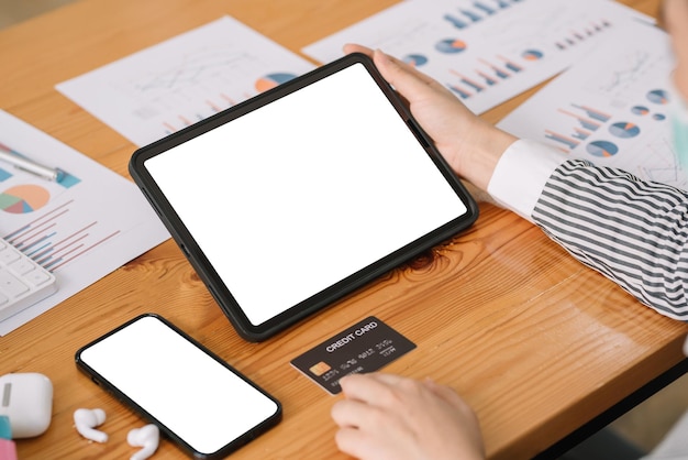 Close up of Woman hand using computer tablet blank white screen and holding credit card shopping online or internet banking on office desk.