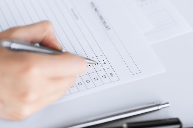 close up of woman hand with blank questionnaire or form