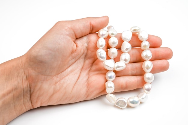 Close up of woman hand with pearl necklace isolated on white Hand with string of baroque pearls