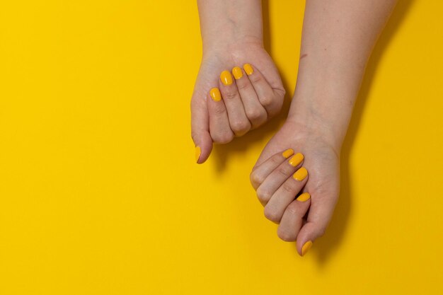 Close-up of woman hand on yellow background