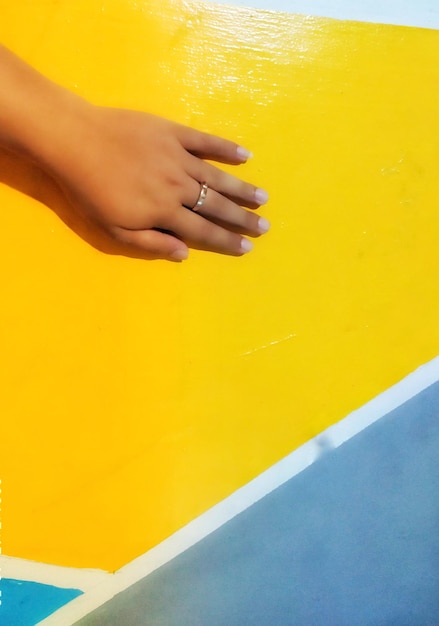 Close-up of woman hand on yellow wall