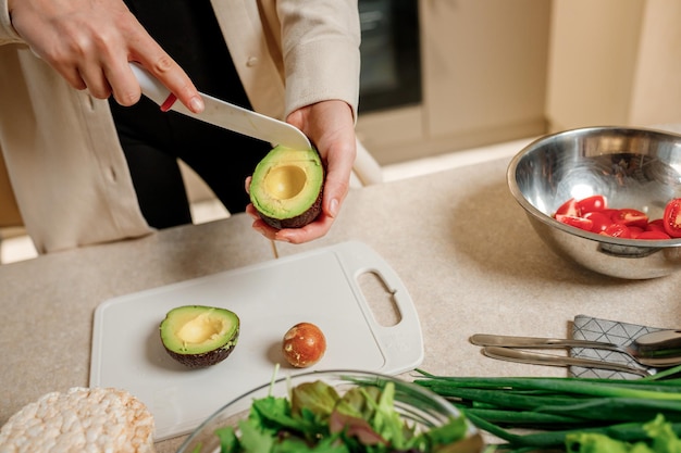 Close up of woman hands cutting fresh avocado in modern kitchen Nutrition And Diet Healthy food concept Ingredients for smoothies