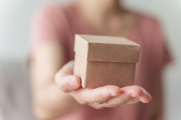 Primo piano delle mani della donna che tengono una piccola confezione regalo. piccola scatola regalo nelle mani della donna.