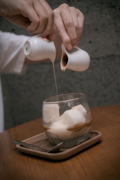 Крупным планом женские руки наливают молоко в холодный лимонный чай или кофе для холодного меню