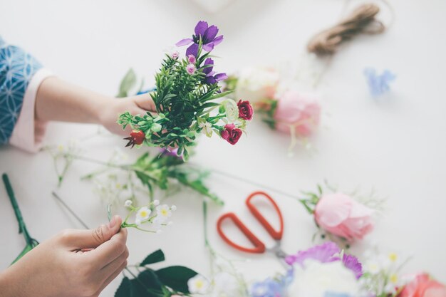Photo close-up of woman hands making flower bouquet over table