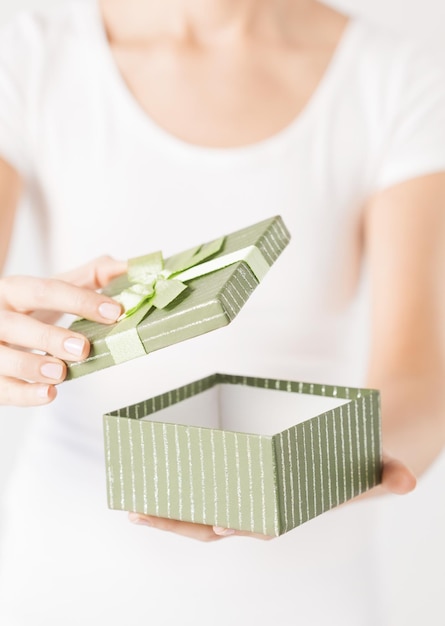 Primo piano delle mani della donna che aprono la confezione regalo.