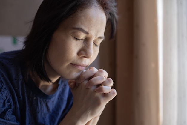 Chiuda in su delle mani della donna pregano in chiesa.