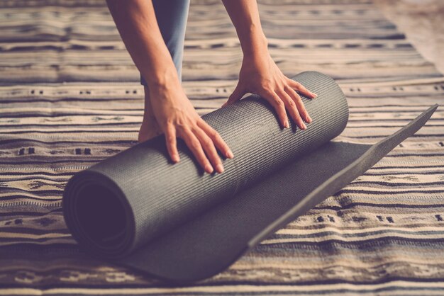 Close up of woman hands taking off yoga mat from the floor after fitness indoor workout active daily session of exercises