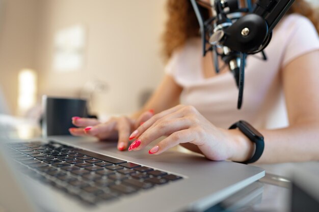 Primo piano delle mani della donna che digitano sulla tastiera del laptop in ufficio