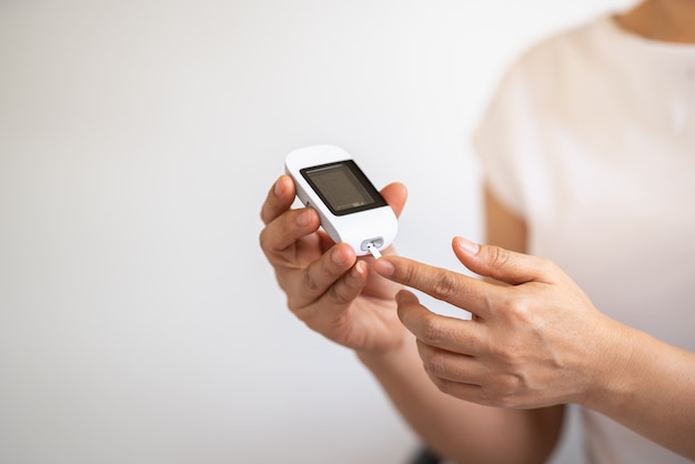 Close up of woman hands using Glucose meter on finger to check blood sugar level