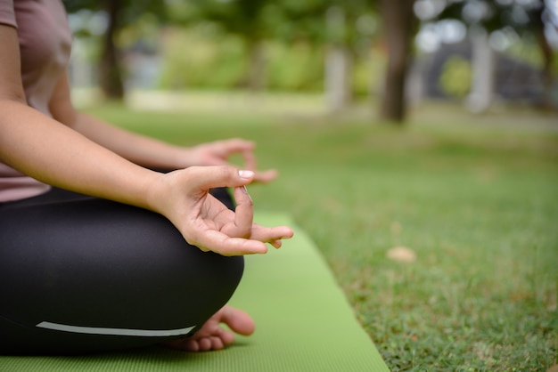 La fine su delle mani della donna fa l'yoga all'aperto nel parco.