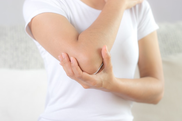 Close up woman having pain in injured elbow. 