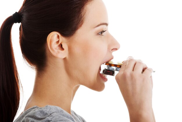 Close-up of woman having pills over white background