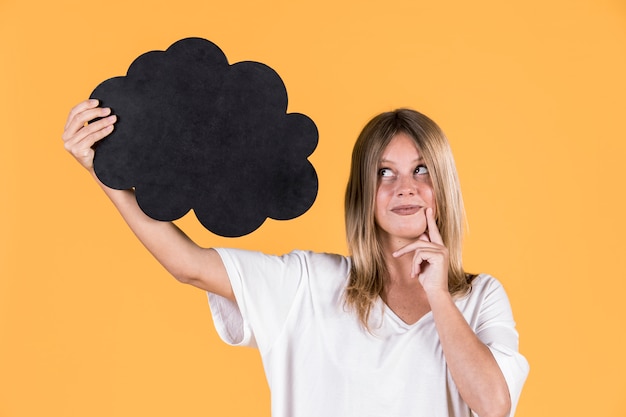 Close-up of a woman holding blank speech bubble over yellow surface