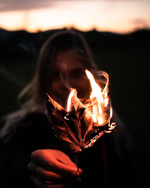 Foto close-up di una donna con una foglia bruciata al tramonto