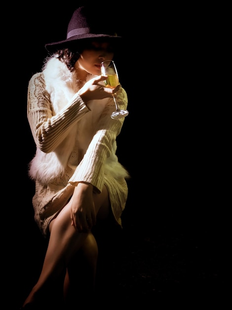 Foto close-up di una donna che tiene un flauto di champagne su uno sfondo nero