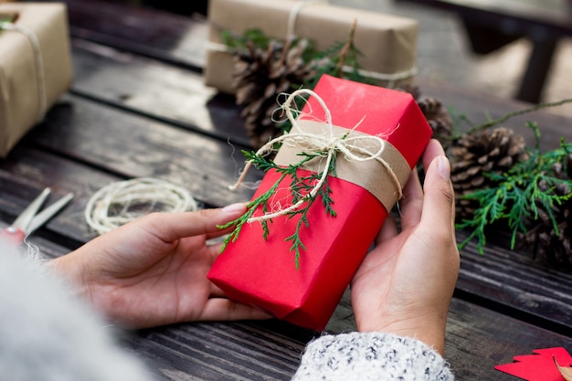 Close up of a woman holding a christmas gift on wooden table