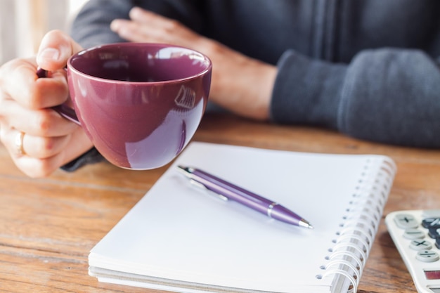 テーブルの上にコーヒーカップを握っている女性のクローズアップ