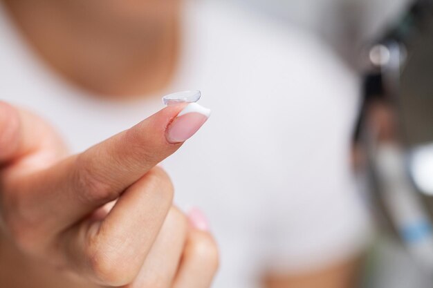 Close up of woman holding contact lens on finger