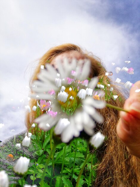 Photo close-up of woman holding flower against sky